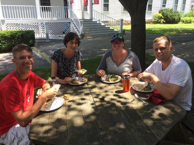 four people eat their lunch of sadnwich wraps outside