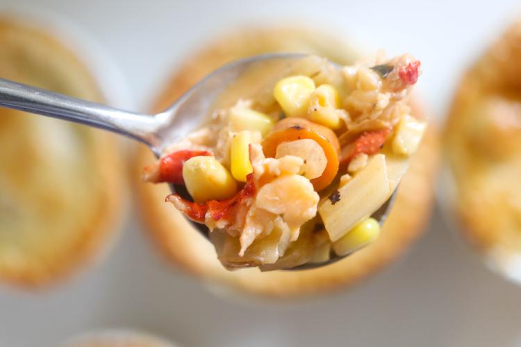 Lobster Pot Pie on a spoon, featuring corn and chunks of lobster meat in a white gravy